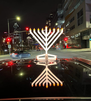 Bright Illumin8 Menorah outdoors on top of Car