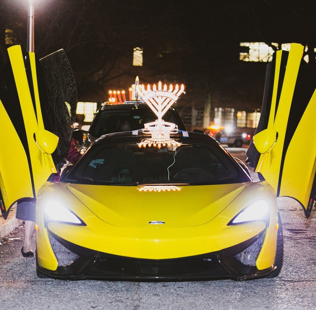 Illumin8 Car Menorah lit up on the roof of a yellow sports car at night