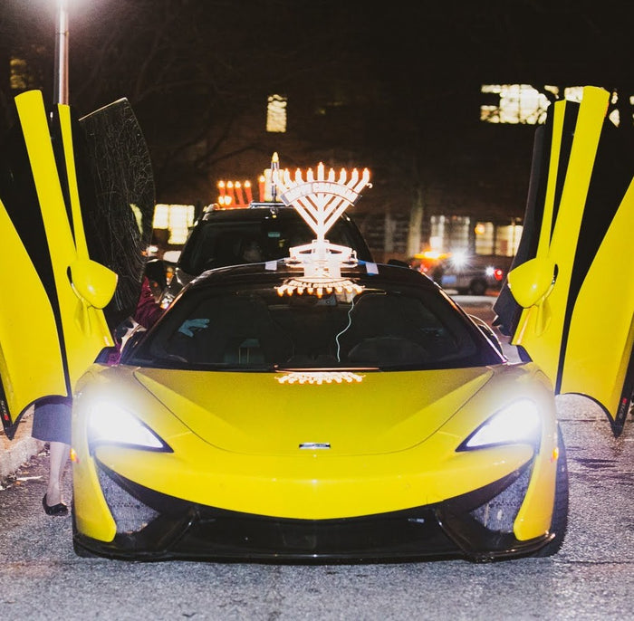 Illumin8 Car Menorah lit up on the roof of a yellow sports car at night