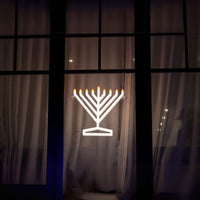 View of the Illumin8 electric Menorah from outside the window, highlighting its visibility on modern home